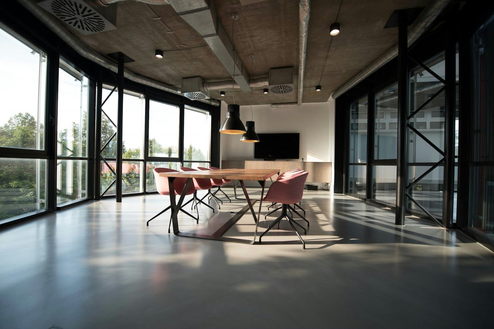 Quiet professional interior with a long table, concrete ceiling and large windows